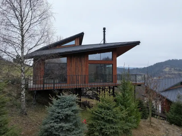 Котедж Тишагора, реальне фото — дерев'яний фасад, синє небо
